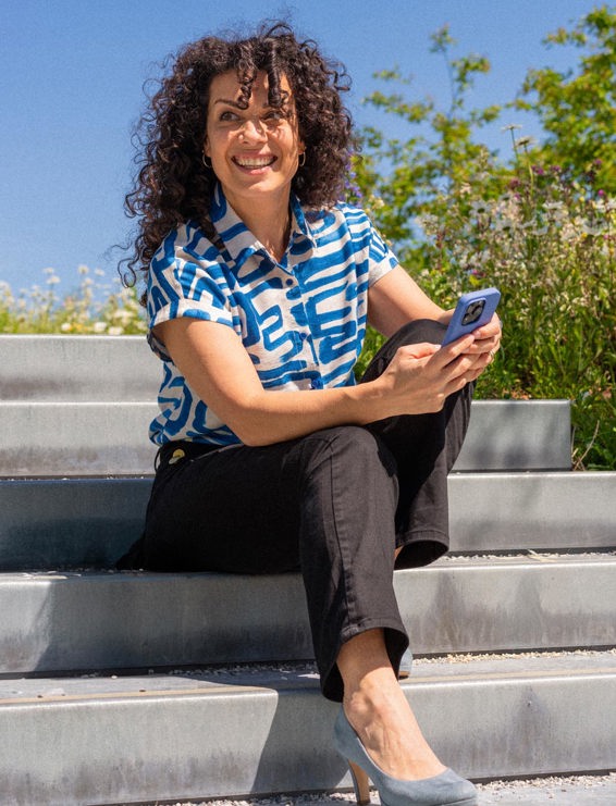 Dariana Kestenholz smiling and looking into the horizon while holding her phone