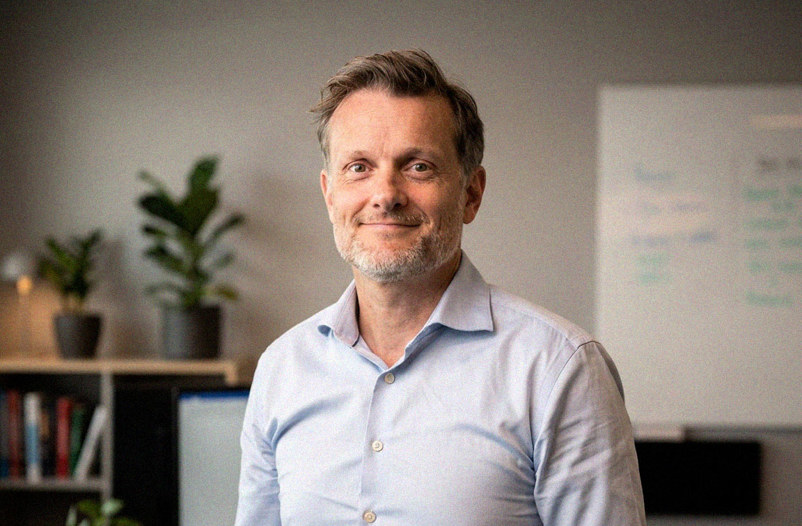 White male in light blue shirt standing in an office