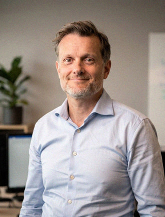 White male in light blue shirt standing in an office