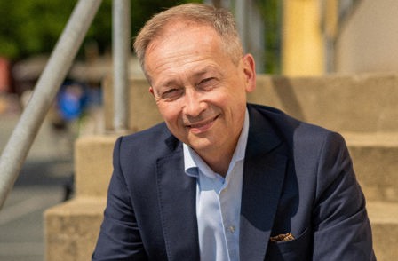 Jakob Schou sitting on the stairs with his hands interlocked looking at the camera