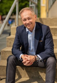 Jakob Schou sitting on the stairs with his hands interlocked looking at the camera