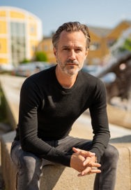 Thomas Quistgaard sitting down looking at the camera with his fingers interlocked