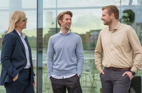 Two men and one woman talking in front of a glass building in Copenhagen